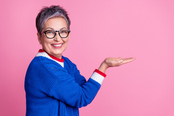 Photo of nice aged lady arms hold empty space wear blue sweater isolated on pink color background