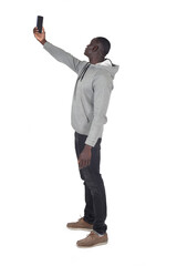 Side rear view of a man taking a self-portrait with his arm raised with a smartphone on white background.