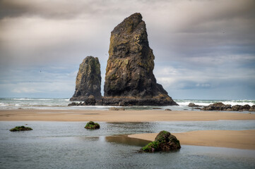 View of several large sea stacks in the ocean at Cannon Beach, Oregon. All sea stacks start out as part of nearby rock formations. Cannon Beach has many examples with haystack Rock as the most famous.