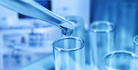 Pipette dripping sample into test tube on color background, closeup