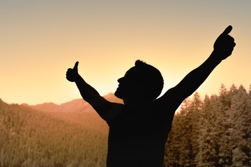 silhouette of a person in the sunset arms raised thumbs up feeling joyful and grateful living a healthy life 