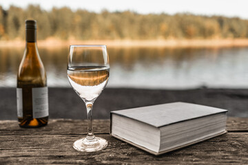 book and glass of wine by a lake, summer holiday travel concept 