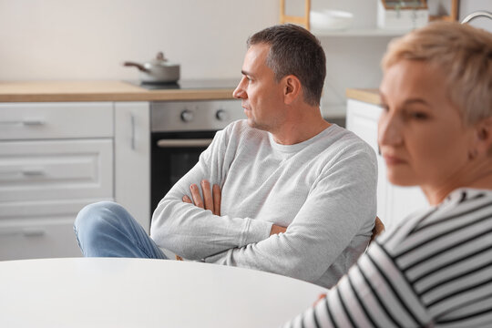 Offended mature man quarreling with his wife in kitchen
