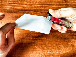 Woman Stapling Papers on a Wooden Desk. A pair of hands using a red stapler to fasten sheets of...