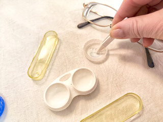 A set for contact lenses with a container, forceps, glasses. The concept of correcting myopia. Contact lens care, cleaning, health. Background, copy space