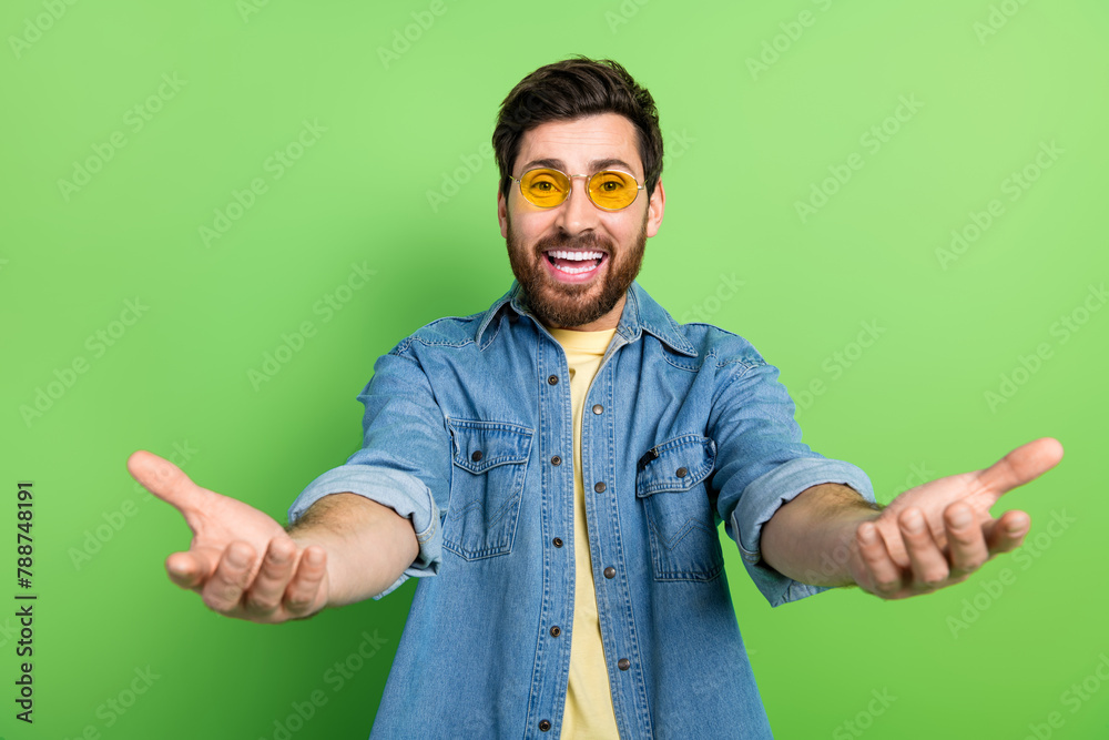 Sticker Photo of positive excited guy dressed jeans shirt open arms ready hug you empty space isolated green color background