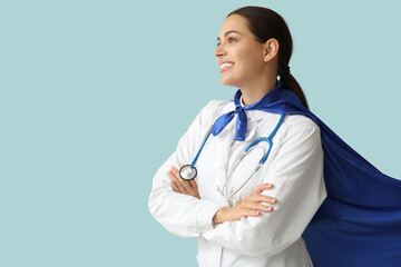 Beautiful female doctor in superhero costume on blue background