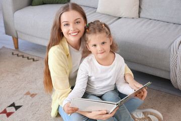 Naklejka premium Little girl with her mother reading book at home