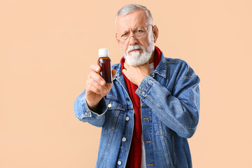 Old man with sore throat holding cough syrup on beige background