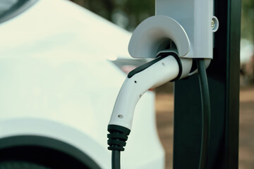 Closeup EV charger handle plugged in or connect to electric car, recharging EV car battery with...