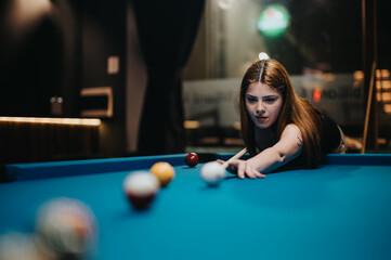 A group of friends plays a fun and carefree game of billiards, focusing on the pool game while enjoying their recreation time together.