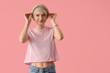 Smiling young woman after chemotherapy on pink background. Stomach cancer concept