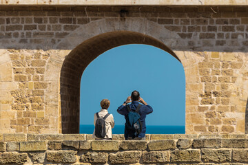 A tourist couple is photographing beach and sea from the bridge in Polignano a Mare, popular spot...