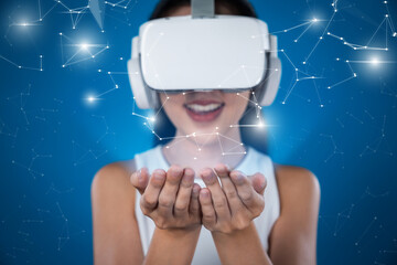 Female stand wear white VR headset, headphone and white suit connect to metaverse, future technology create virtual reality space. She look at her palms like it has object on her hands. Hallucination.