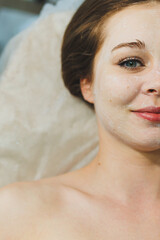 Naklejka premium Close-up of a young woman's face during a facial cleansing procedure in a beauty salon. A beautician in black gloves wipes a client's face with a napkin. Therapeutic facial skin care.