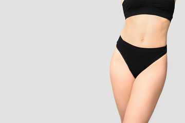 Fototapeta premium Beautiful young woman in black cotton underwear on light background