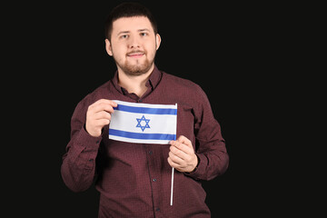 Young Jewish man with flag of Israel on black background