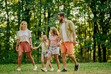 An active family holding hands and taking a walk in nature.