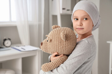 Little girl after chemotherapy with toy bear in clinic, closeup. International Childhood Cancer Day