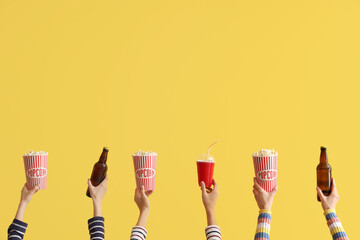 Many hands with buckets of popcorn and beer on yellow background