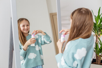 Teen Girl Applying Lotion in Front of Mirror. Morning preparation before school.