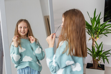 Child Trying on Glasses in Front of Bedroom Mirror. Morning preparation before school.