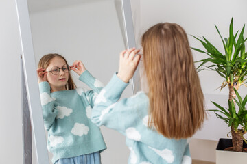 Morning routine. Child Adjusting New Glasses Looking in Mirror. Morning preparation before school.