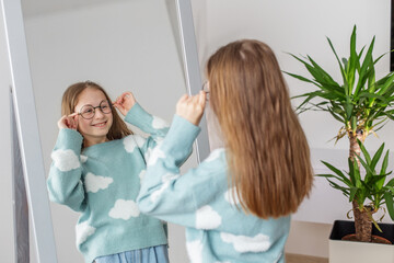 Smiling Child Trying on Round Glasses at Home. Morning preparation before school.