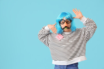 Funny little girl in disguise with party blower and sticky paper on blue background. April Fools'...