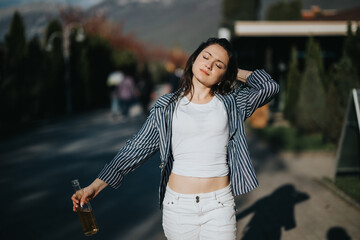A young woman relaxes on a sunny street, eyes closed and feeling the warmth of the sun, holding a cold beverage in a casual outfit.