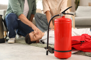 Fire extinguisher and people helping unconscious man in room, closeup