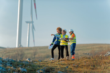 A team of engineers and workers oversees a wind turbine project at a modern wind farm, working together to ensure the efficient generation of renewable energy - obrazy, fototapety, plakaty
