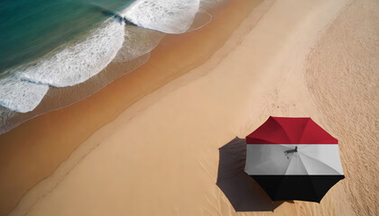 An aerial vista of a sandy beach with gentle ocean waves, featuring a beach umbrella adorned with the Yemen flag. Ideal for Yemen tourists seeking seaside relaxation