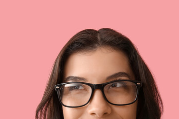 Beautiful young woman in eyeglasses on pink background, closeup