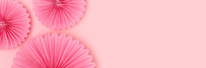 Tissue paper fans scattered on a pink background. Banner with place for text.