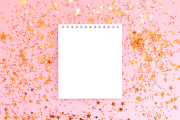 Clean notepad mockup and shiny golden stars confetti on a pink background. Festive concept.