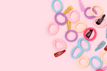 Small multicolored hair scrunchies and clips on a pink background. Place for text.