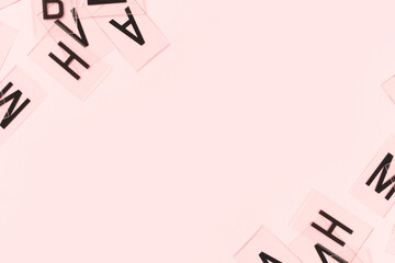 Transparent plastic cards with letters scattered on a pink background. Creative concept with copy space.