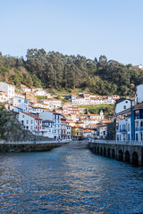 Fototapeta premium Sunny day captures Cudillero's charm, vibrant houses against contrasting coastline, coastal town.