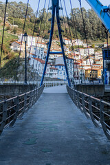 Coastal bridge scenery: Azure metal bars contrast with Cudillero's picturesque rural landscape.