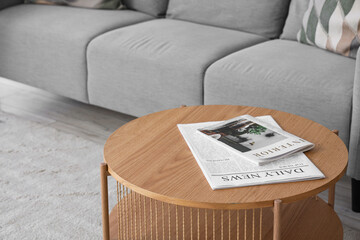 Wooden coffee table with fashion magazine and newspaper in living room, closeup