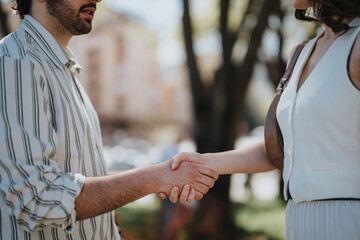 Close-up image of business executives shaking hands, symbolizing agreement and cooperation outdoors.