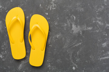Bright yellow flip-flops on concrete background, top view. Summer concept