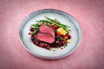 Traditionally roasted saddle of venison fillet with spätzle, vegetable and fruits in chocolate red...