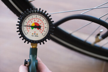 Hand Holding Tire Pressure Gauge with Bicycle Tire in Background