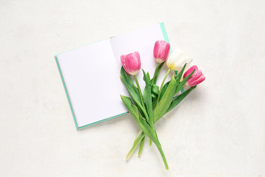 Notebook with beautiful tulips on white background. Mother's Day celebration