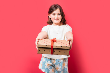 Young girl offering a gift box on red background
