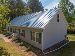 Fototapeta na wymiar New steel metal light blue roof on a single family home featuring 5V style panels. 