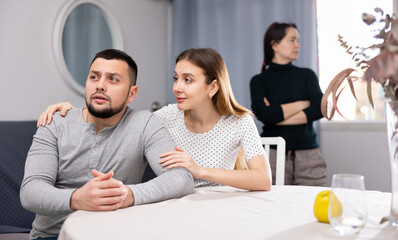 Worried young woman embracing, comforting and soothing her upset stressed husband while their...