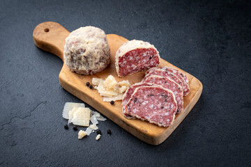 Traditional Italian saltufo salami with parmesan coated and truffle served as close-up on a rustic wooden cutting board
